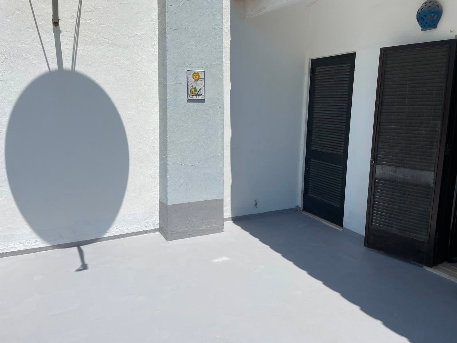 Freshly painted terrace floor and whitewashed walls beside dark louvred shutters on an Algarve house
